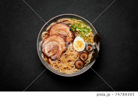 A Shoyu Ramen in gray bowl on black table top. Japanese cuisine meat noodle soup with chashu pork 74789305