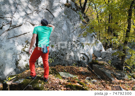Athletic middle aged male climber stands in front of a large training rock before free mountain climbing in the forest in autumn Athletic middle aged male climber stands in front of a large training rock before free mountain climbing in the forest in autumn 74792300