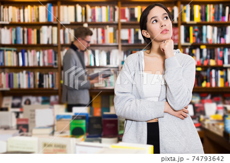 pensive girl in interior of bookstore pensive girl in interior of bookstore 74793642