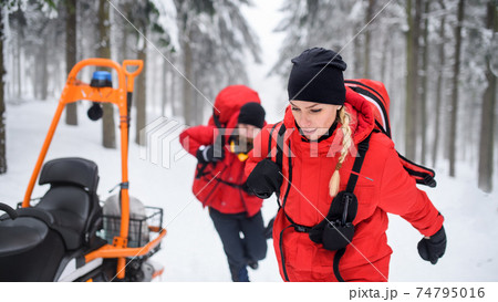 Paramedics from mountain rescue service provide operation outdoors in winter in forest. Paramedics from mountain rescue service provide operation outdoors in winter in forest. 74795016