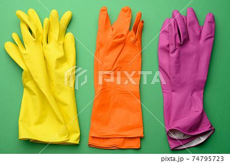 three pairs of rubber gloves for cleaning on a green background, top view three pairs of rubber gloves for cleaning on a green background, top view 74795723