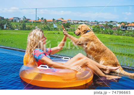 Dog give high five to happy girl swimming in pool Dog give high five to happy girl swimming in pool 74796665
