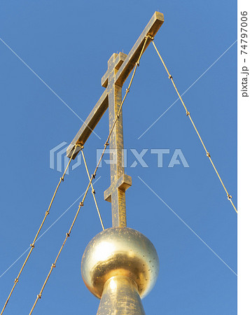 Golden dome with orthodox cross close-up on a blue sky background 74797006