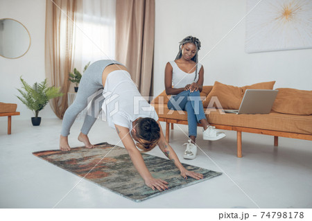 Short-haired young girl doing yoga and standing in downward dog pose 74798178