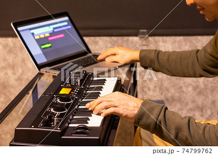 male musician enjoy playing keyboard synthesizer for arranging a song on laptop computer in home studio. music production technology male musician enjoy playing keyboard synthesizer for arranging a song on laptop computer in home studio. music production technology 74799762