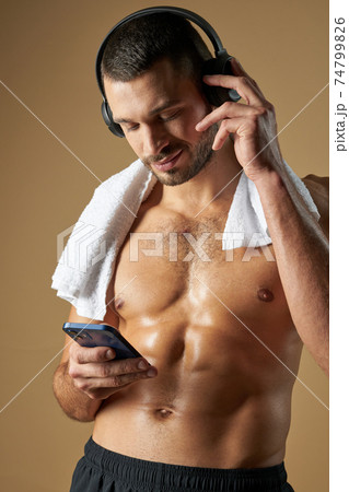 Funny adorable man with muscular body looking to the screen smartphone on yellow background Funny adorable man with muscular body looking to the screen smartphone on yellow background 74799826
