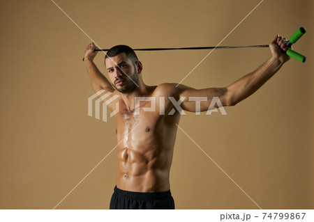 Focused strong sportsman holding skip rope above the himself in the studio 74799867