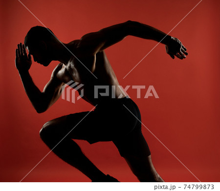 Handsome unrecognized athlete in action isolated on red background of a studio 74799873