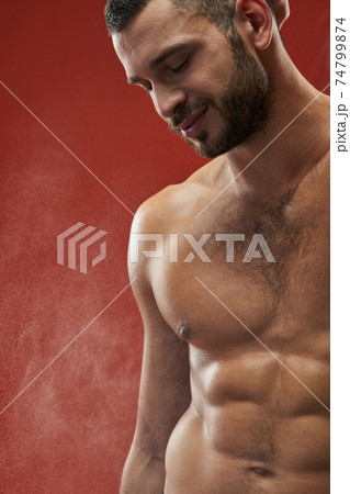 Happy smiling athlete man showing his embossed body in the indoors Happy smiling athlete man showing his embossed body in the indoors 74799874