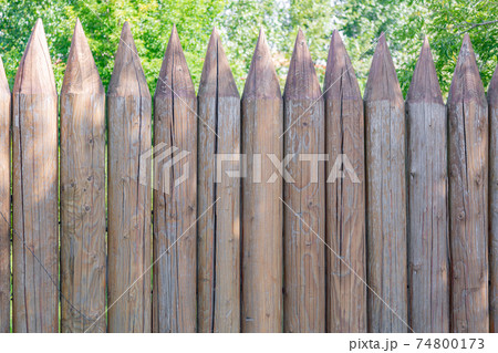 Wooden fence made of sharpened logs Wooden fence made of sharpened logs 74800173