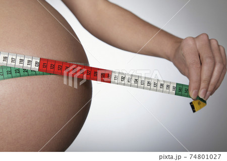 Pregnant Woman Measuring Belly With Tape Measure 74801027