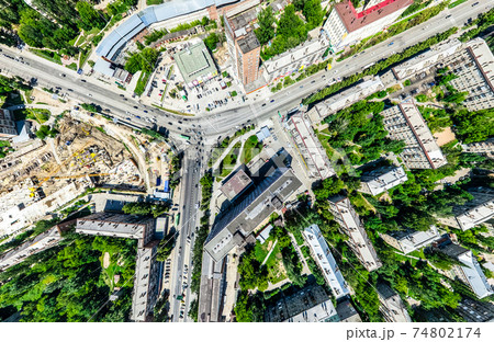 Aerial city view with crossroads and roads, houses, buildings, parks and parking lots. Sunny summer panoramic image 74802174