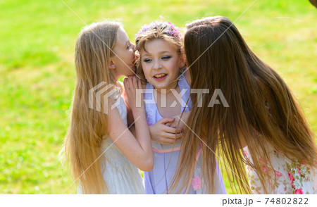 Three adorable girls in dresses hold hands in the garden, park. Three adorable girls in dresses hold hands in the garden, park. 74802822