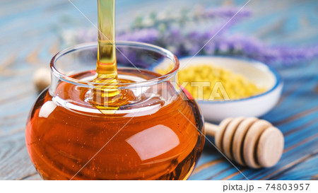 Honey in glass jar with honey dipper over wooden background Honey in glass jar with honey dipper over wooden background 74803957