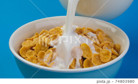 Milk pouring into bowl of corn flakes 74803980