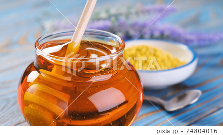 Honey in glass jar with honey dipper over wooden background Honey in glass jar with honey dipper over wooden background 74804016