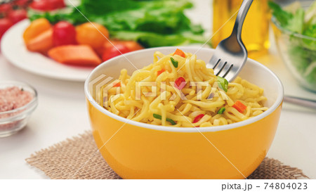 Instant noodles with fork, served with vegetables and herbs Instant noodles with fork, served with vegetables and herbs 74804023