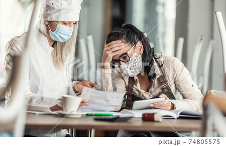 Gastronomy business owners in a desparate situation over bills sitting in a closed restaurant Gastronomy business owners in a desparate situation over bills sitting in a closed restaurant 74805575