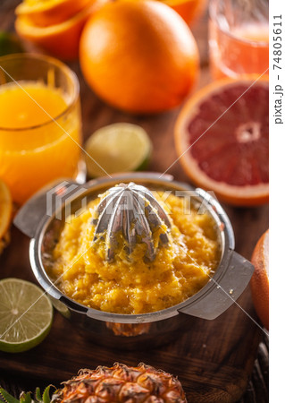 Squeezed orange pulp in a juicer with cfreshly cut citruses and a glass of juice Squeezed orange pulp in a juicer with cfreshly cut citruses and a glass of juice 74805611