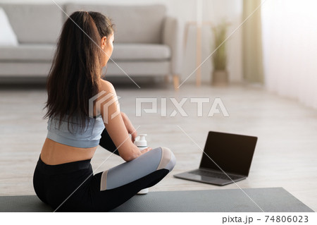 Unrecognizable woman in sportswear looking at laptop with empty screen Unrecognizable woman in sportswear looking at laptop with empty screen 74806023