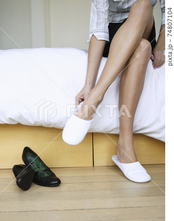 Woman Putting On Slippers In Bedroom Woman Putting On Slippers In Bedroom 74807104