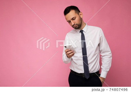 Photo of handsome good looking man wearing casual white shirt and tie isolated on pink background 74807496