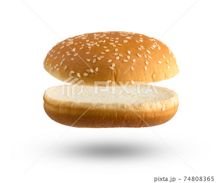 Burger bun on a white background. Two halves of a burger bun flying over a white background. 74808365