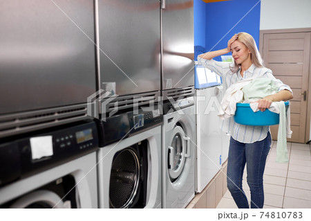 young european woman doing laundry, looking sad and depressed expression. young european woman doing laundry, looking sad and depressed expression. 74810783