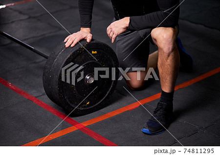 Cropped sportsman adding weight to barbell changing black plates, equipment for weight training concept 74811295