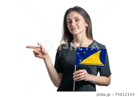 Happy young white woman holding flag Tokelau and points to the left isolated on a white background 74812143