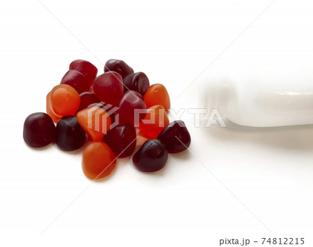 Group of red, orange and purple multivitamin gummies with the bottle isolated on white background. Healthy lifestyle concept. 74812215
