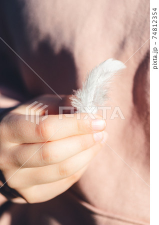 Light white feather in young girl hands Light white feather in young girl hands 74812354