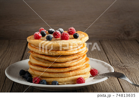 Stack of pancakes with fresh berries on a white plate on the table, copy space Stack of pancakes with fresh berries on a white plate on the table, copy space 74813635
