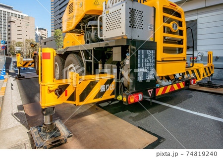 工事現場でアウトリガー使用中のクレーン車の写真素材