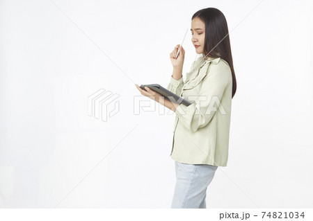 Beautiful young woman holding digital tablet and looking at camera with smile while standing. Wireless technology. 74821034