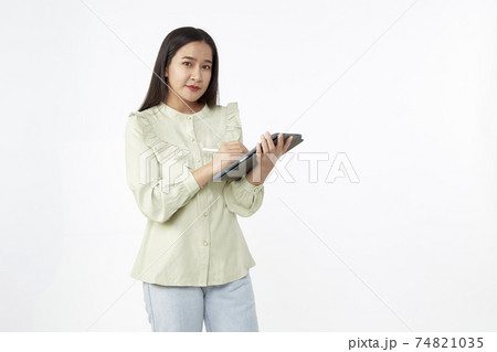 Beautiful young woman holding digital tablet and looking at camera with smile while standing. Wireless technology. 74821035