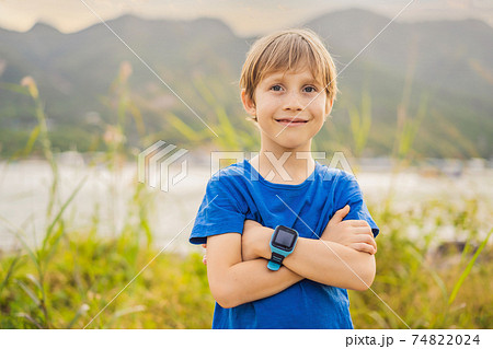 Boy uses kids smart watch outdoor against the background of the garden 74822024