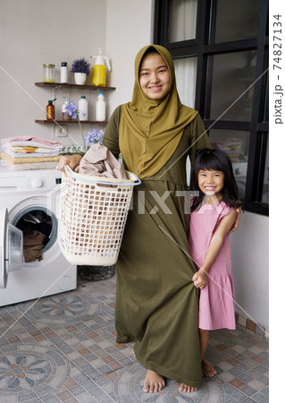 muslim asian mother and child girl little helper in laundry room 74827134