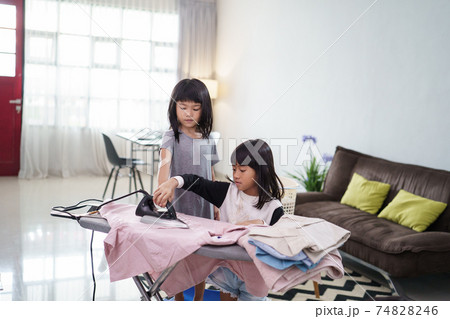 girl smiling happily as she doing the ironing at home 74828246
