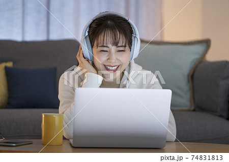 ヘッドホンをつけてノートパソコンの画面を見る女性 74831813