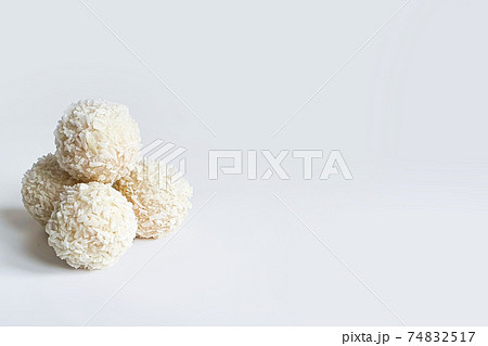 Handmade candies. Sweet balls, white Chocolate candies with coconut crumb on white isolated background. Copy space in right side. Selective focus Handmade candies. Sweet balls, white Chocolate candies with coconut crumb on white isolated background. Copy space in right side. Selective focus 74832517