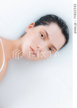 Close up female face in the milk bath with soft white glowing. Copyspace for advertising. Beauty, fashion, style, bodycare concept. 74832592