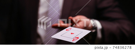 Man in business suit catche red ace playing card. 74836278