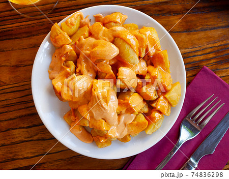 Spanish cuisine patatas bravas served with sauce on plate on wooden table 74836298