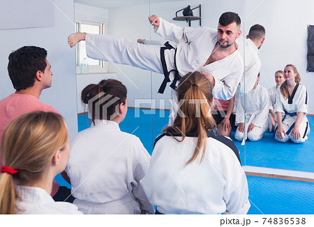 Male instructor 20-29 years old is showing new martial moves to adults 74836538