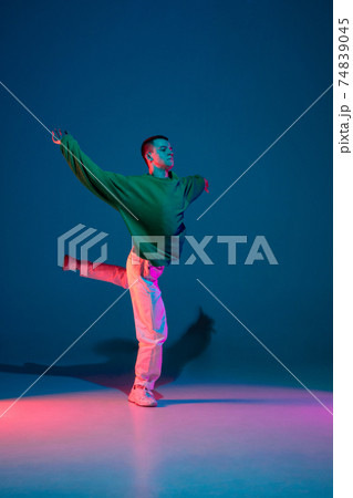 Stylish sportive boy dancing hip-hop in stylish clothes on colorful background at dance hall in neon light. Youth culture, movement, style and fashion, action. 74839045
