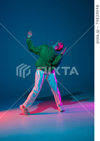Stylish sportive boy dancing hip-hop in stylish clothes on colorful background at dance hall in neon light. Youth culture, movement, style and fashion, action. 74839048