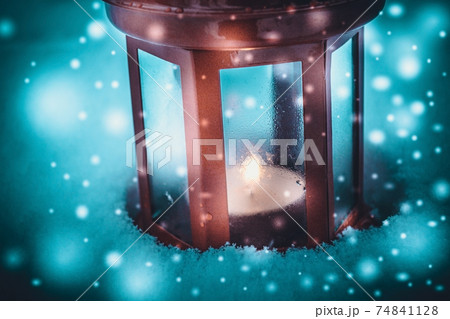 Red candle lantern with candle in snow during snowfall 74841128