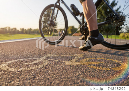 Close up of a bicycle sign drawn on asphalt. Professional male cyclist standing with his road bike on a cycle path 74843292