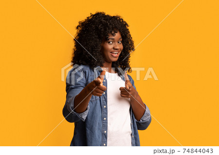 Cheerful black woman indicating at camera on yellow Cheerful black woman indicating at camera on yellow 74844043